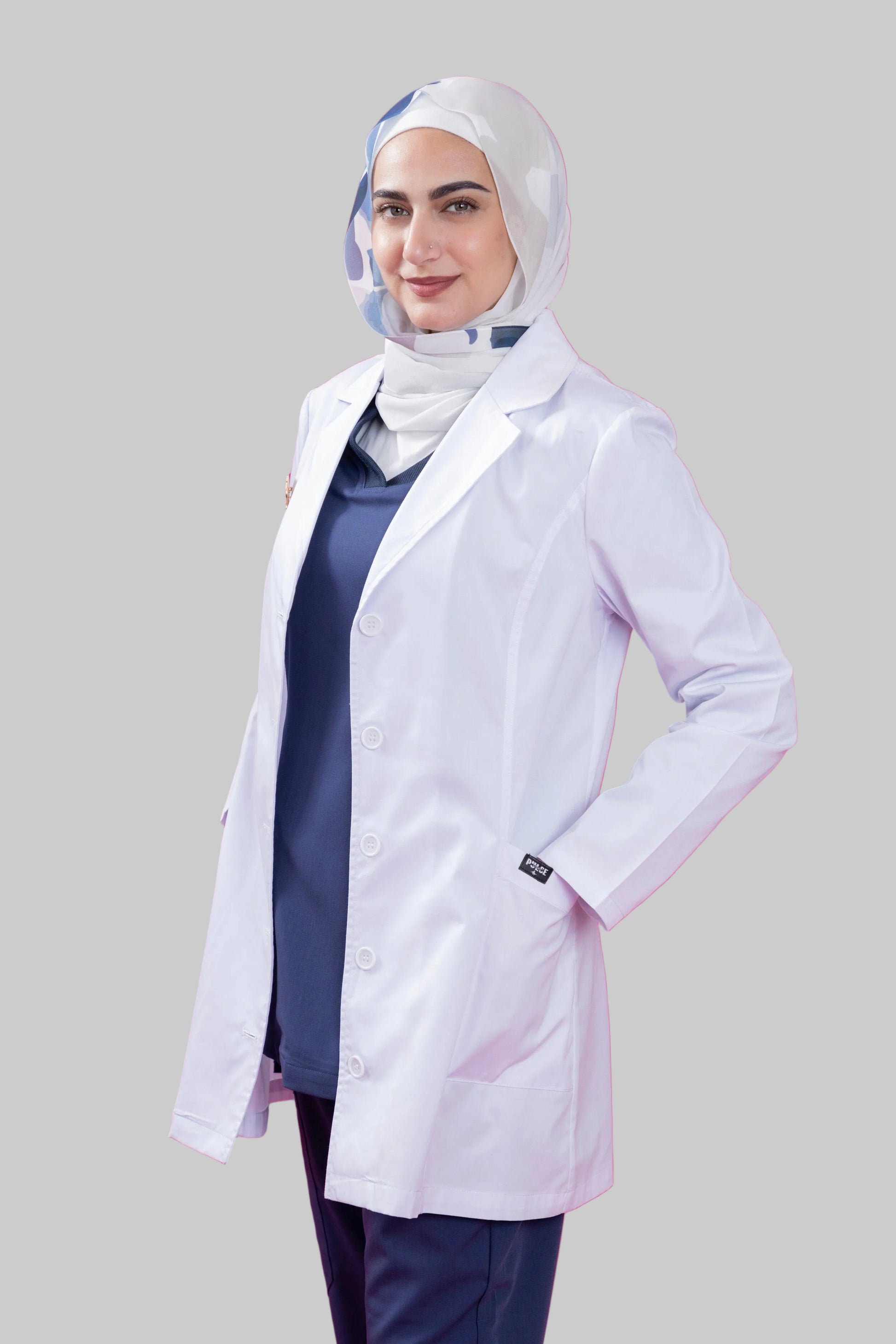 Person wearing a white lab coat over a dark outfit on a pink background