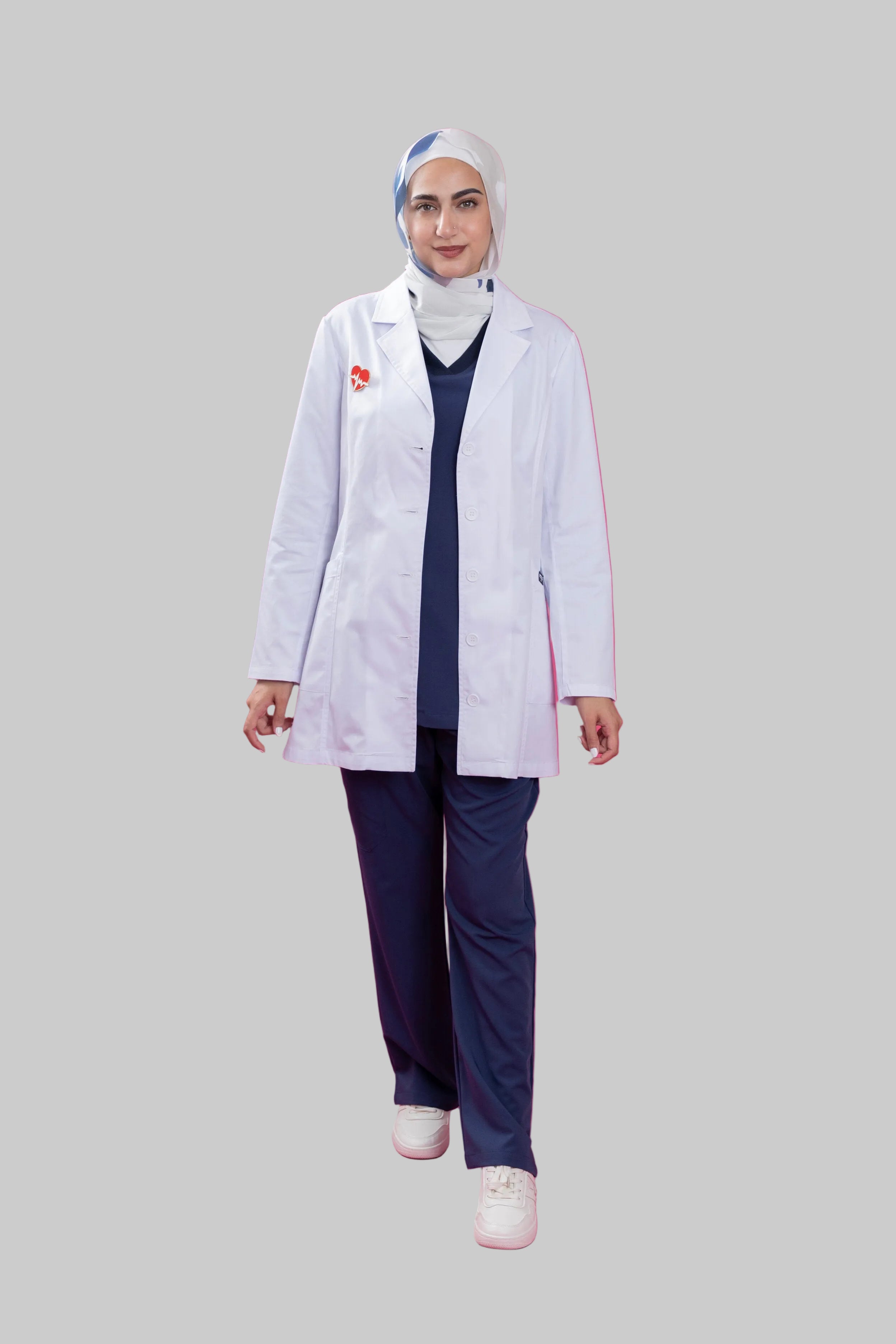 Person wearing a white lab coat and navy pants on a pink background