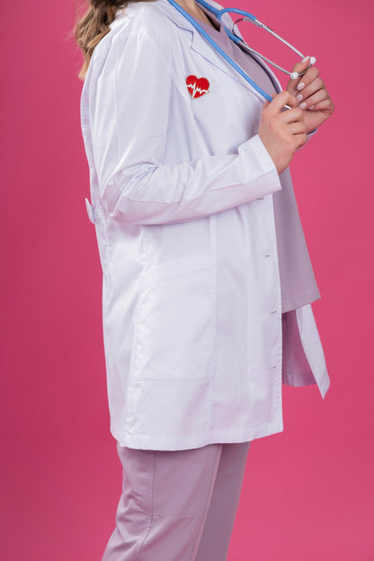 Person wearing a white lab coat with a red heart logo on a pink background