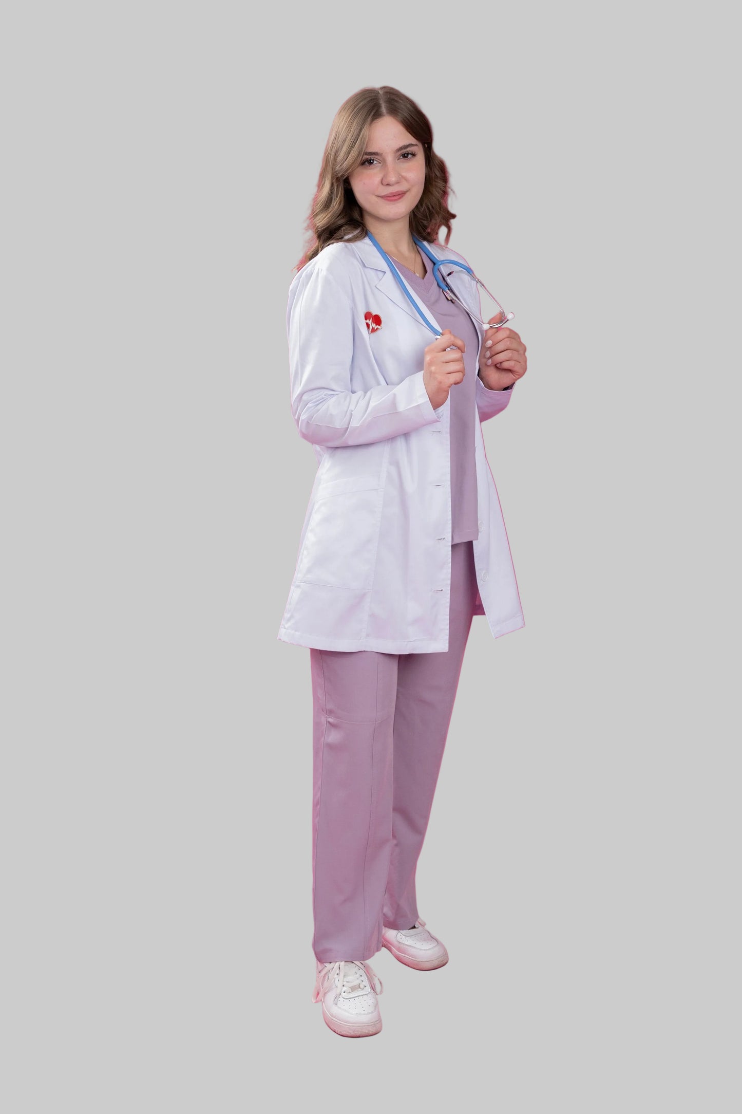 Person wearing a white lab coat and light purple pants on a pink background