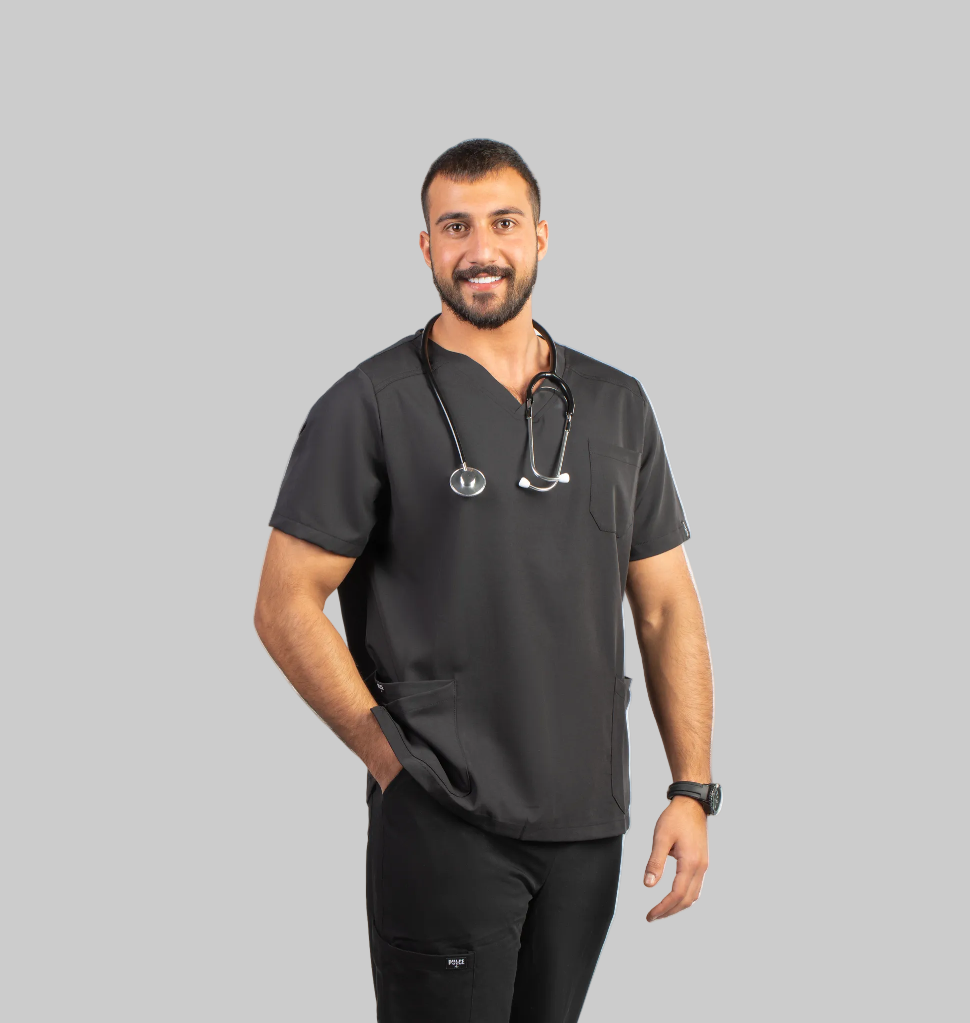 Man wearing dark gray scrub top and black pants with a stethoscope, standing against a white background with 'Pulse' branding.