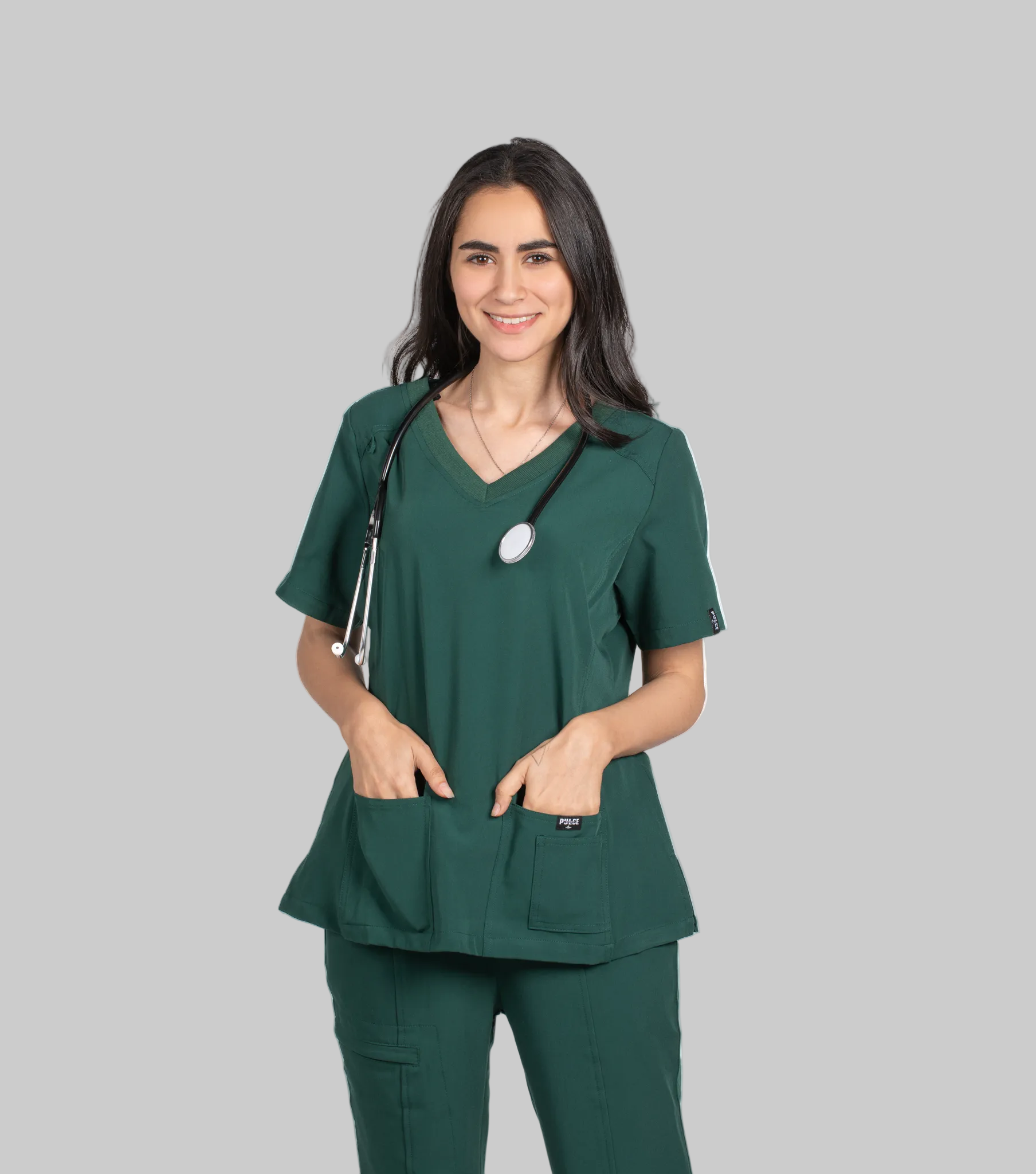 Woman wearing green medical scrubs with a stethoscope, branded 'Pulse', on a white background.